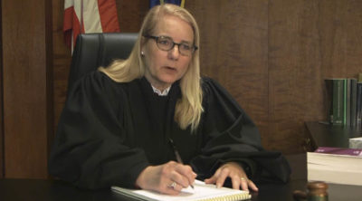 A judge sitting at her bench talking with a juvenile victim of sex trafficking