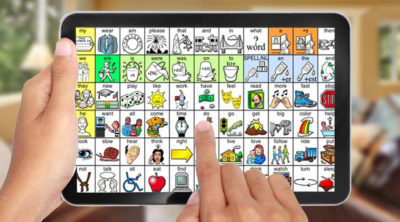 A person is holding an Augmentative and Alternative Communicatiolns device