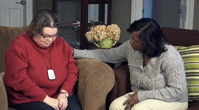 A caregiver is talking with a young, sad woman with disabilities