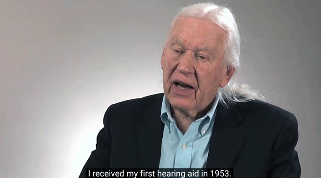 Photo of Dr. Sam Trychin talking about his life. A caption reads "I received my first hearing aid in 1953"