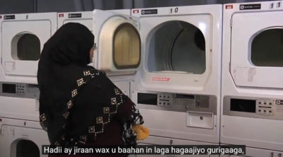 A Somali woman is loading laundery to a washing machine